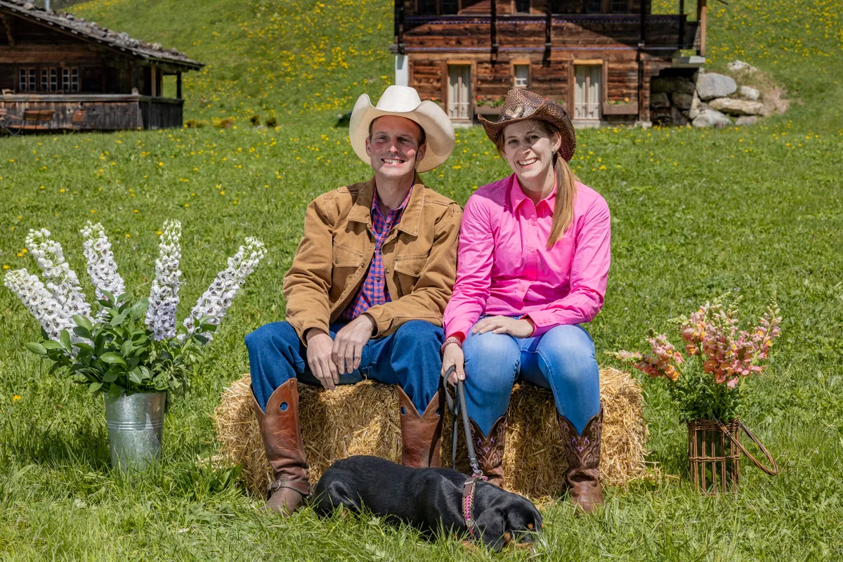 Ein Bauer und eine Bäuerin auf Heuballen sitzend.